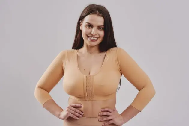 BodyAid arm lift compression crop in beige with 3/4 sleeves & posture support. Front three row hook and eye adjustment. Ideal for Brachioplasty and Liposuction to the arms.